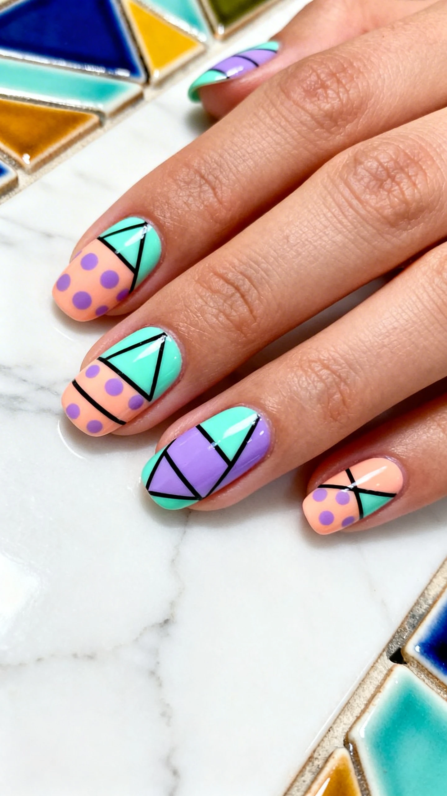 A beautiful macro photograph of one hand showing a nail design featuring Abstract Easter Egg Geometrics. The nails are adorned with sharp, intersecting lines, triangles, and polka dots in neon mint, lavender, and peach, mimicking modern egg patterns. High-resolution, sharp focus on the nails. Aesthetic background of a sleek white marble surface with colorful geometric ceramic tiles. Modern, Instagram-worthy photography style. No faces visible, focus ONLY on the nails and hand., macro nail photography, high quality, Instagram-worthy, clean composition